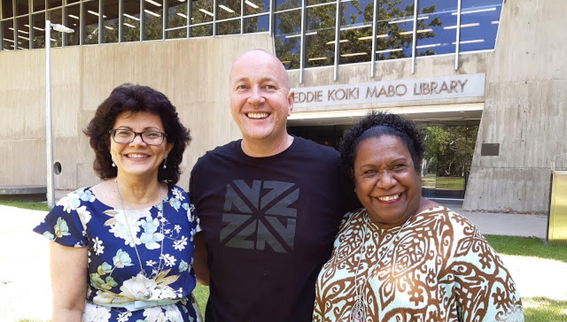 Helen Hooper, Rob Douma, and Gail Mabo smile while standing in front of the Mabo Library