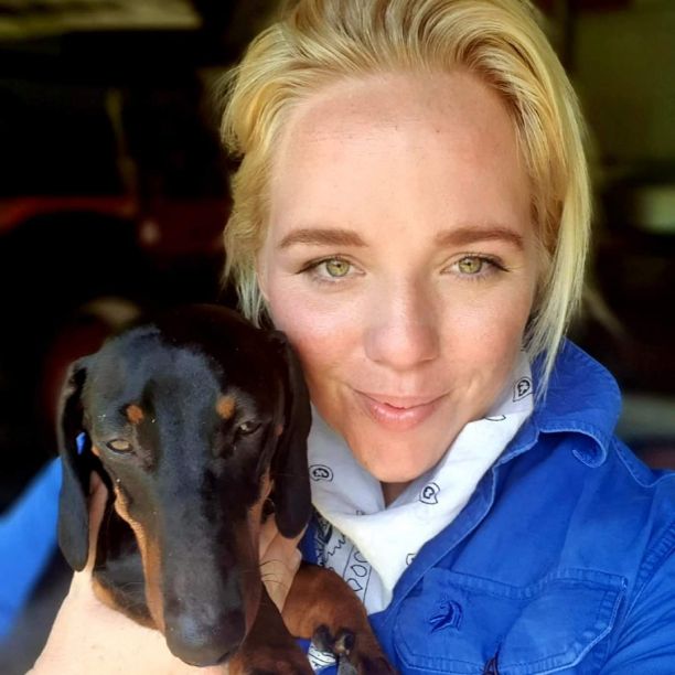 A selfie of Sarah with a black dachshund. 