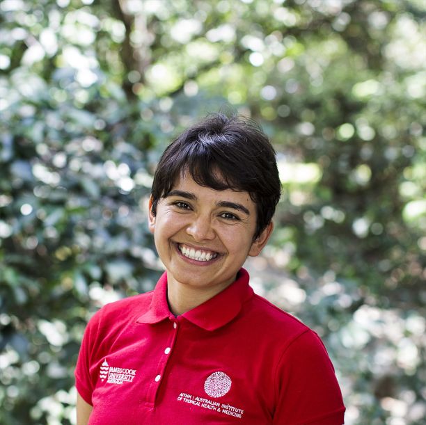 A portrait of JCU PhD Student Linda Hernández Duran. She has a big smile and is standing in front of a lush greenery-filled background. 