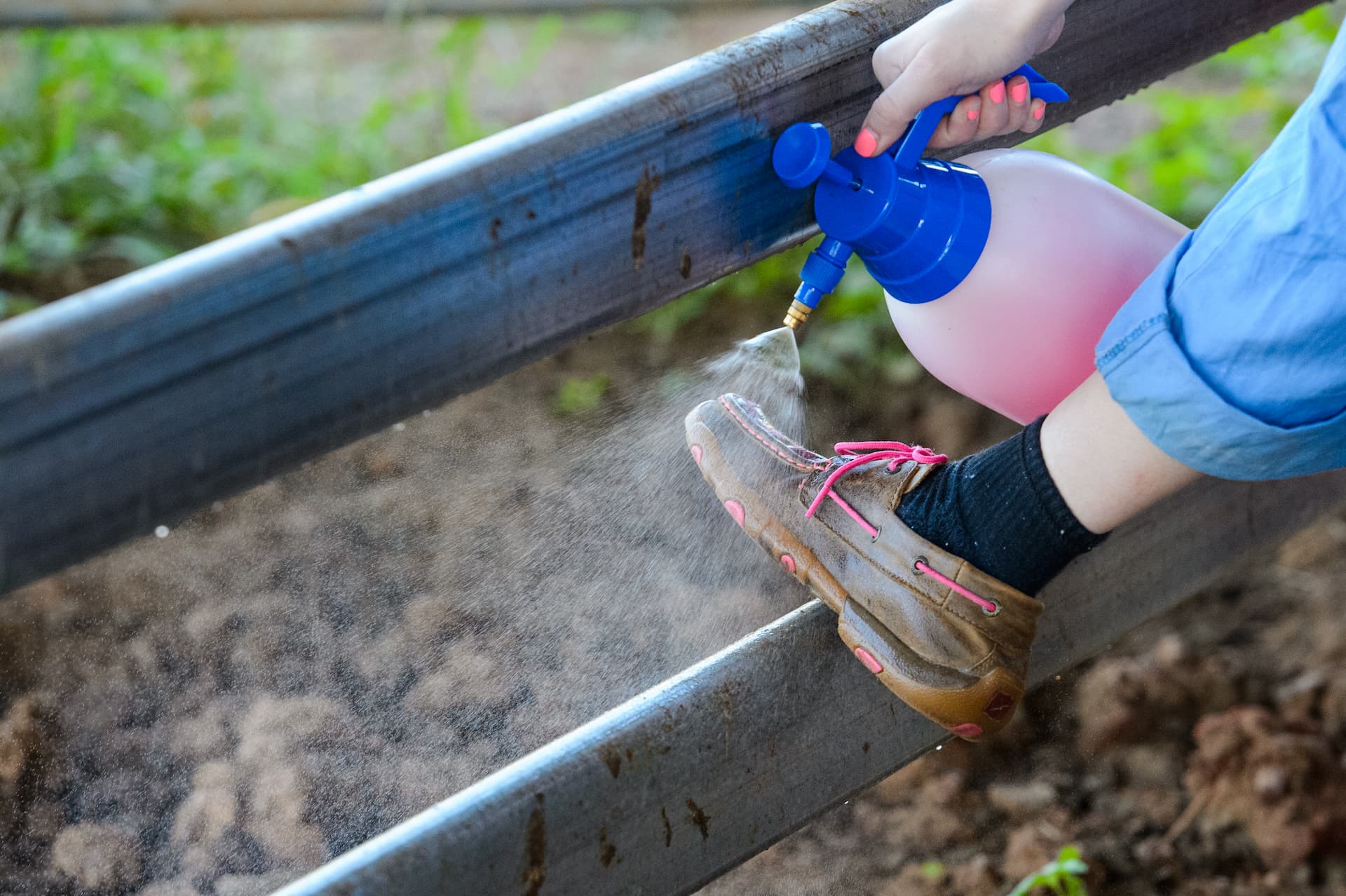 A lady spraying her shoe with a chemical. 