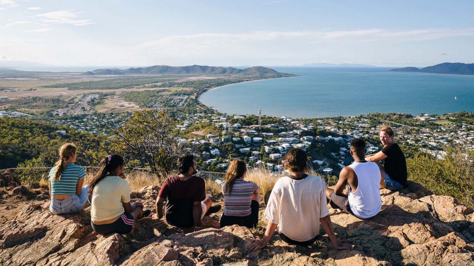 Students sit atop Castle Hill with views of the city, ocean and green landscape. 