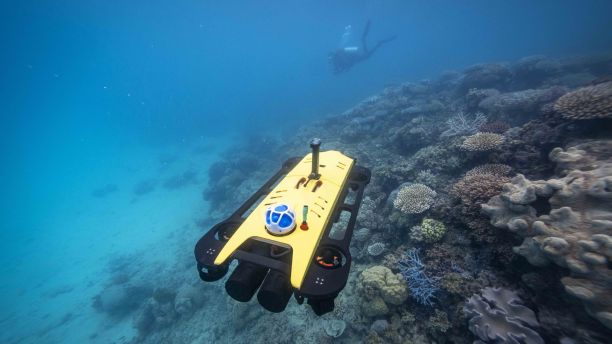 AIMS ReefScan CoralAUV is a small yellow underwater drone surveying a coral reef underwater near Lizard Island. 