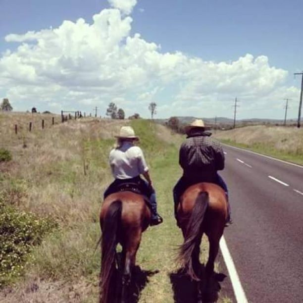 Sarah riding a horse along the side of the road on her families farm in Queensland. 