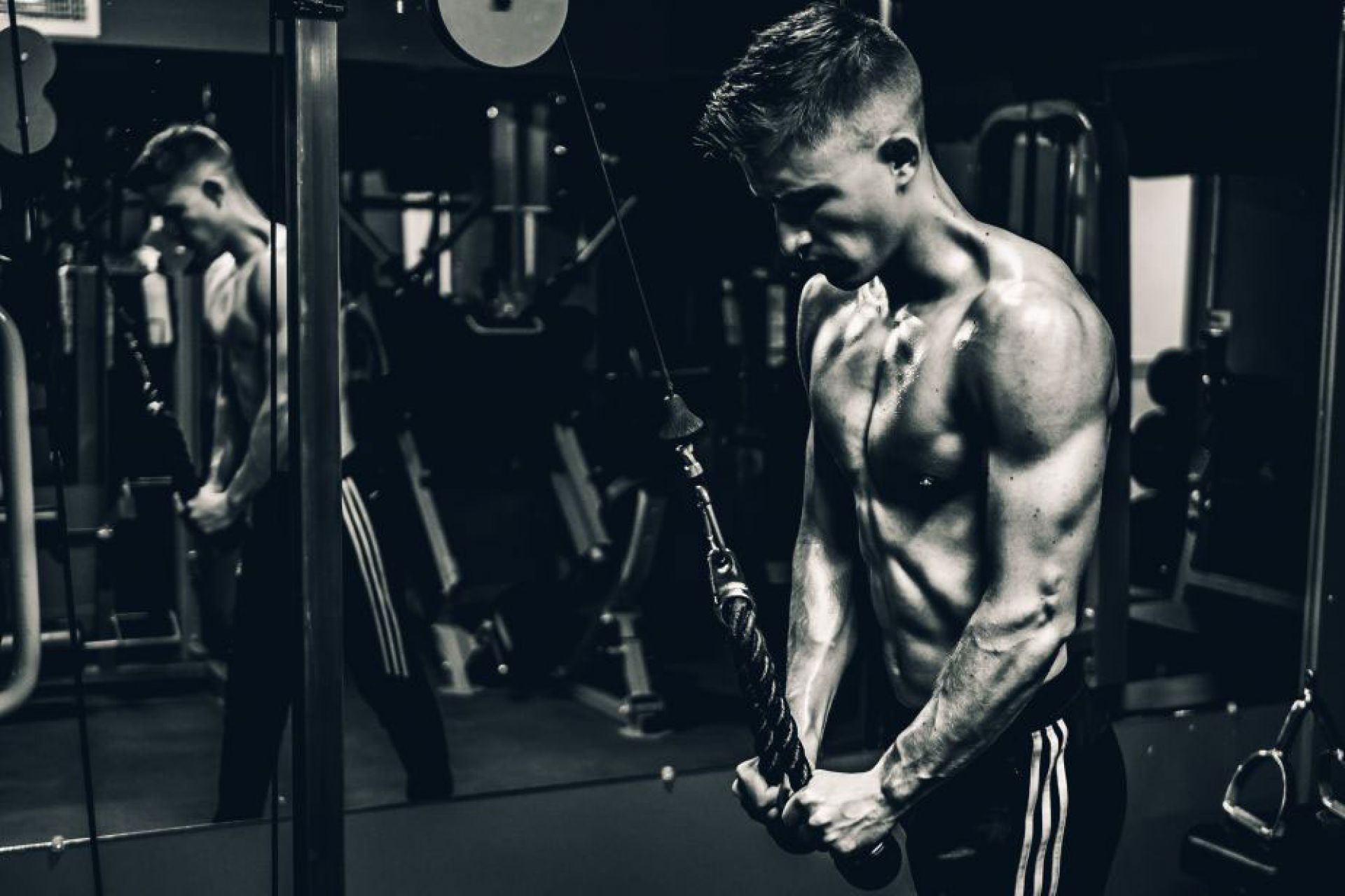 black and white photo of a muscular man working out in a gym