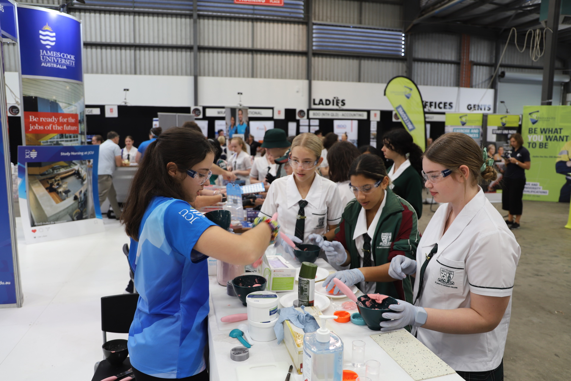A JCU Ambassador showing dentistry moulds to high school students at a dentistry booth.