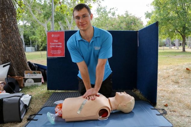 Matthew Riggs poses in CPR chest compression position at a mannequin 