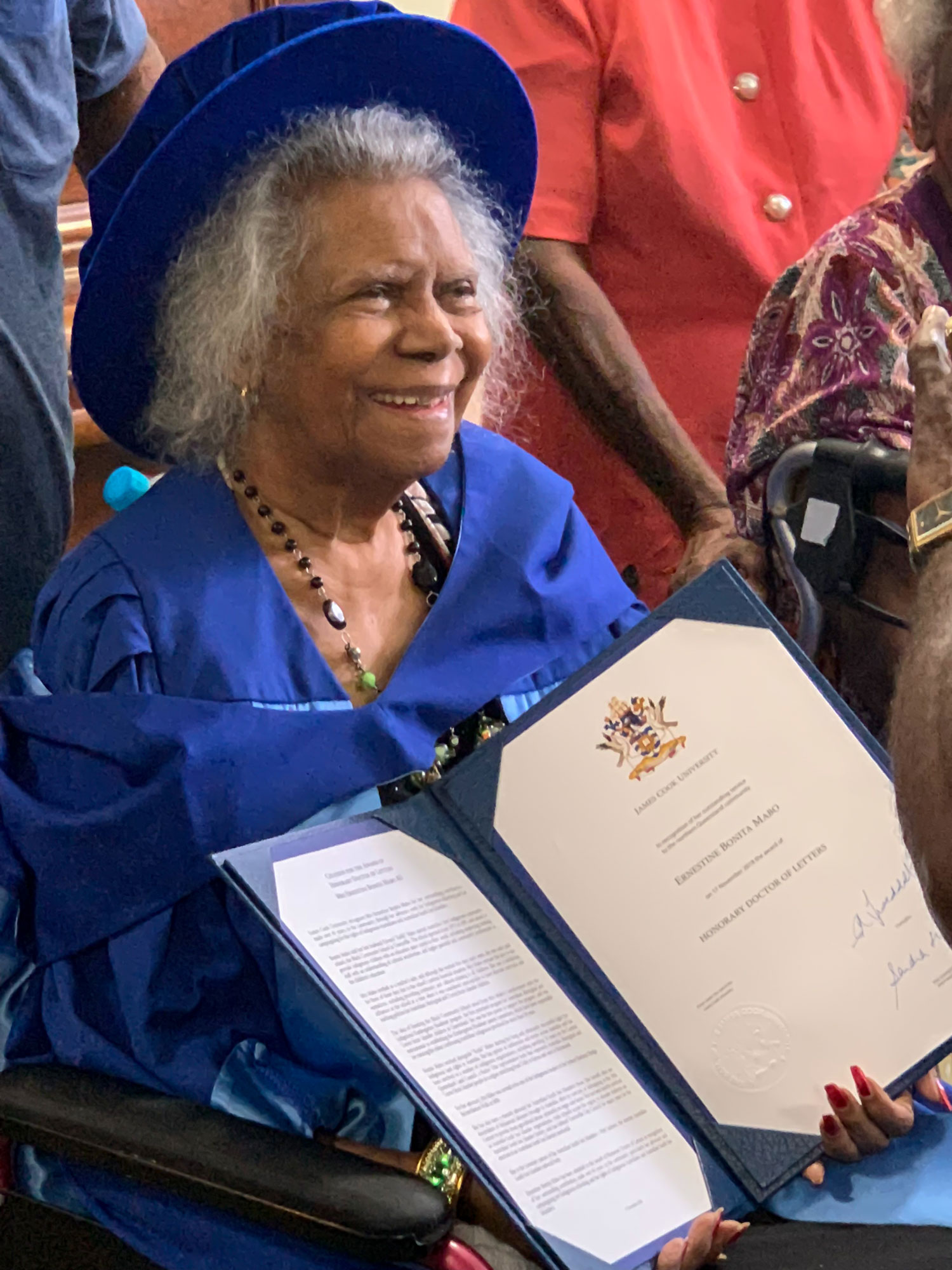 Dr Bonita Mabo wearing academic dress and holding her Honorary Doctorate from JCU