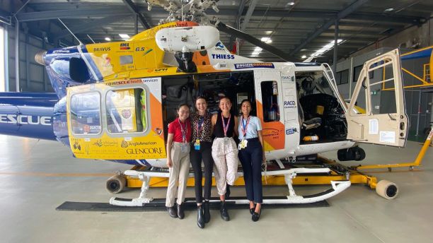 four medical students in front of rescue helicopter in hangar