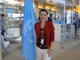  JCU Bachelor of Arts and Bachelor of Science graduate standing with UN flag