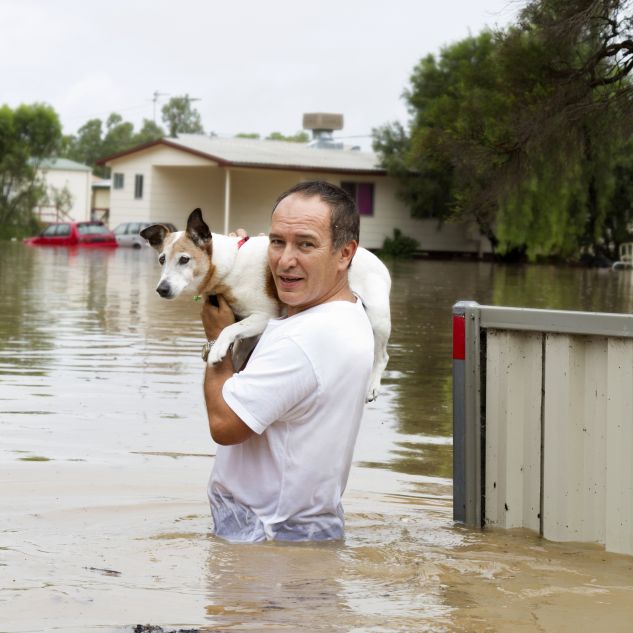 A man carries his dog through waist-high floodwater