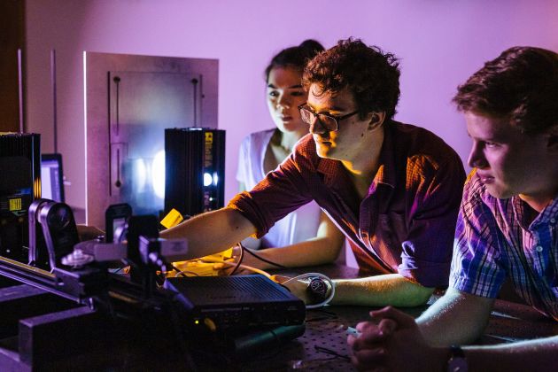 Students in the Physics lab looking at computer equipment. 