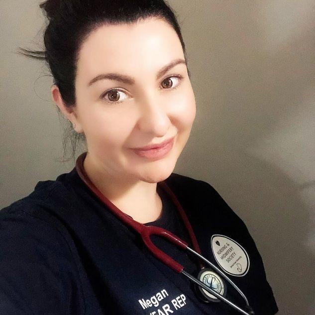 Megan Lee smiling with her hair in a bun and wearing a navy nurses outfit with a red stethoscope. 