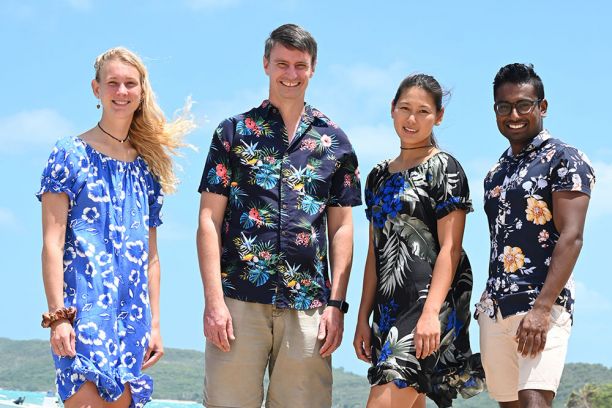 Four people in tropical outfits on beach