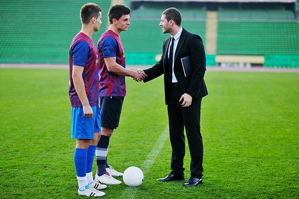 Sport manager in business suit with football players