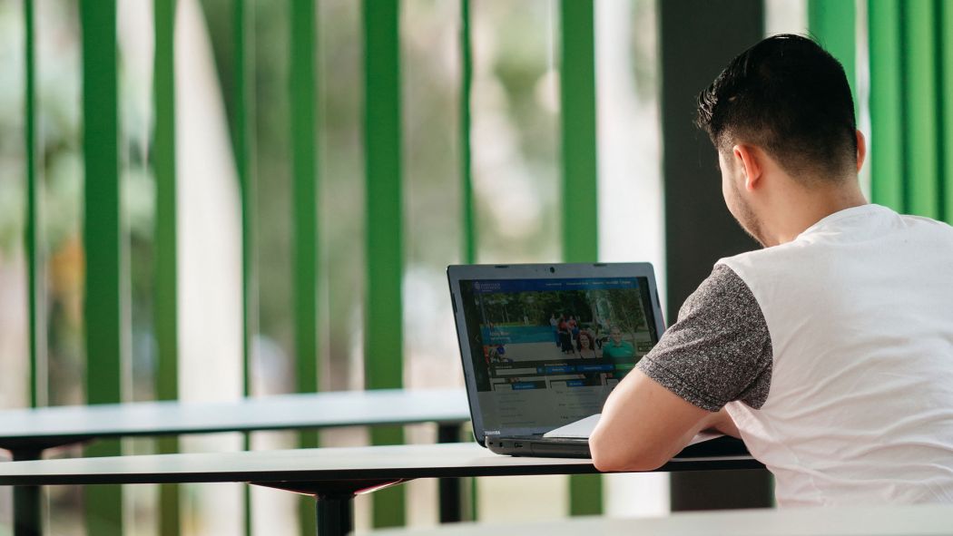 Male student facing computer while studying in the Verandah Walk at JCU Townsville, Bebegu Yumba campus, Douglas. 
