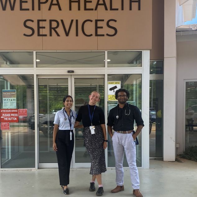 three young people standing in front of Weipa Health Services entrance sign