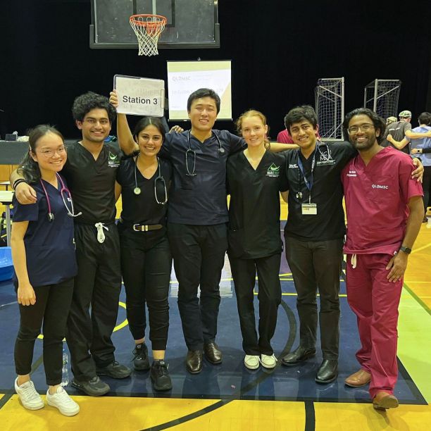 Group of medical students in scrubs on basketball court holding a sign that says Station 3 