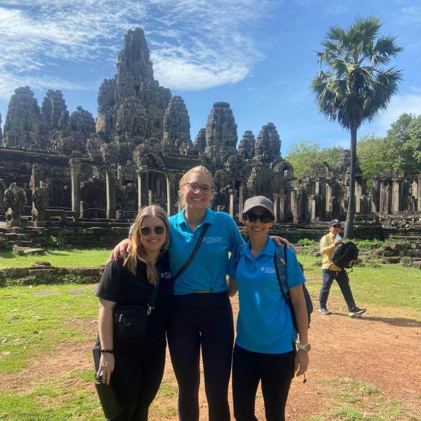 Three JCU students smiling and standing in front of temples in Cambodia. 
