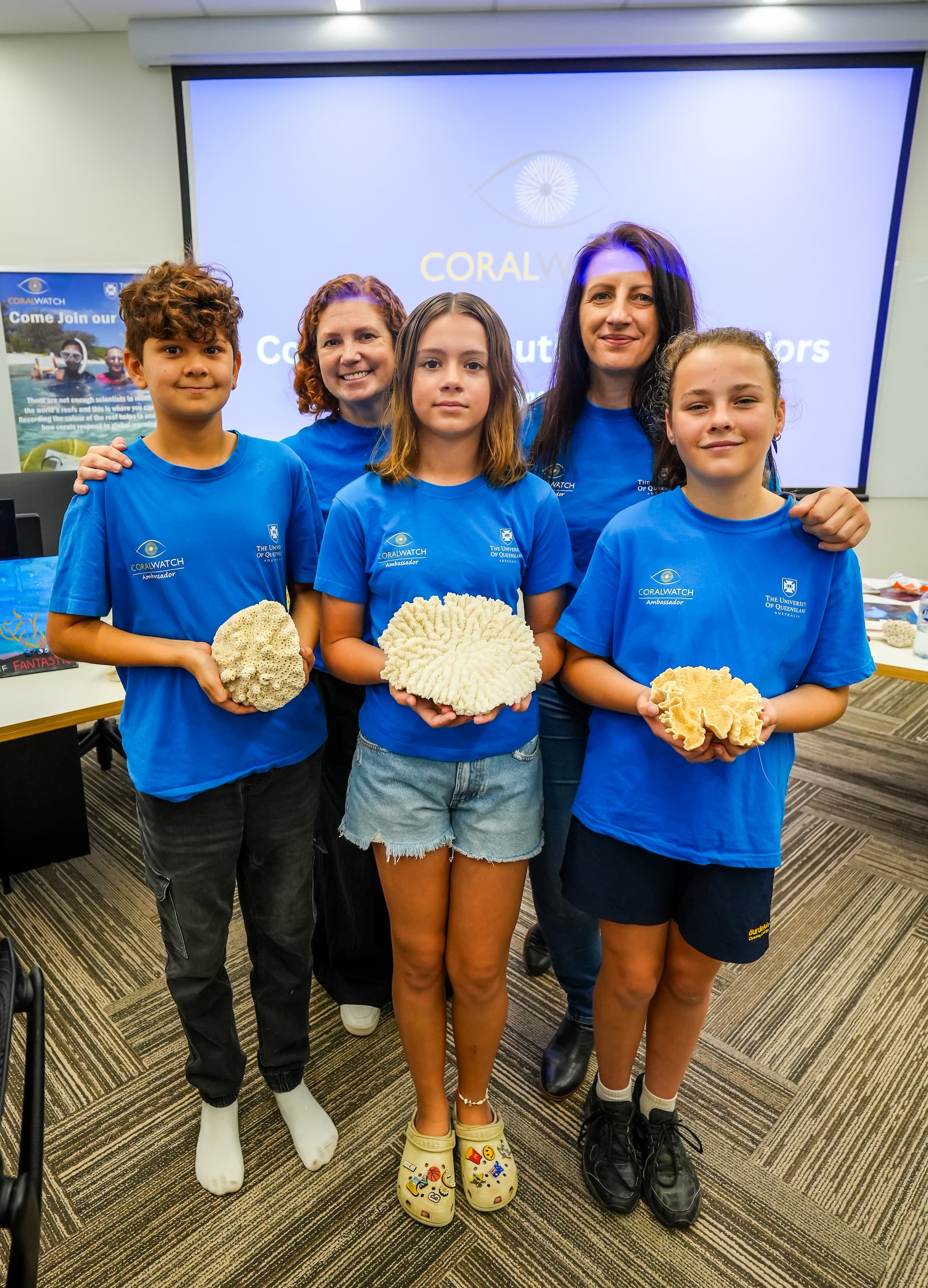 Dr Allison Paley holding coral with school children. 