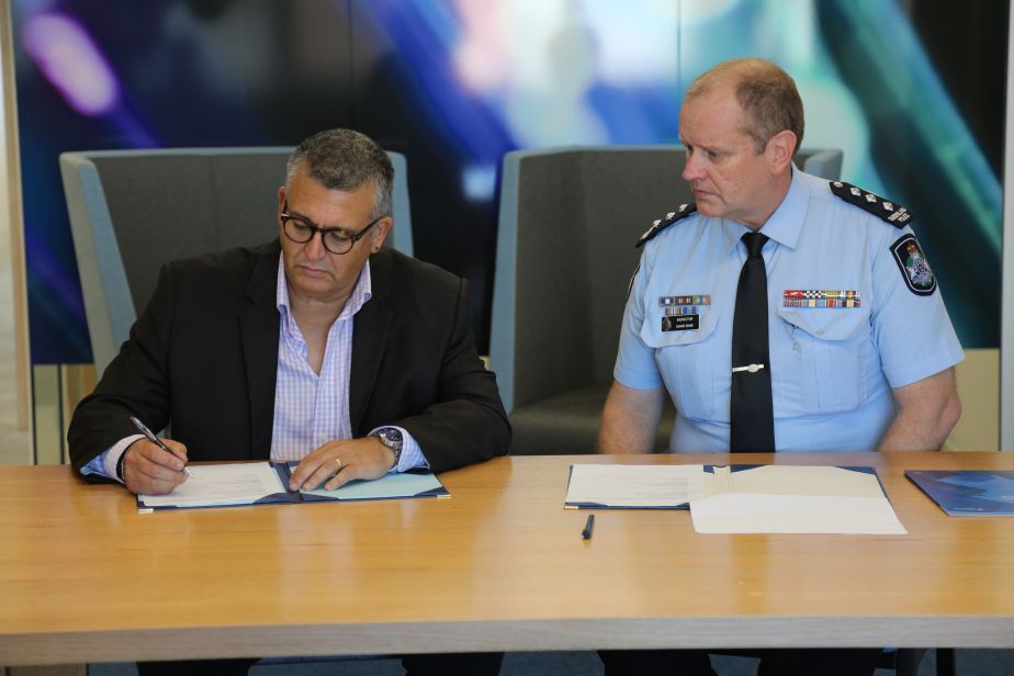 Professor David Low signs the agreement as Inspector Danny Shaw looks on. 