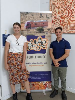 young man and woman in front of Purple House banner