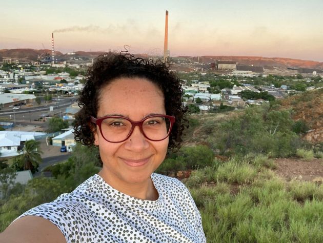 woman with sunset and mining town with smokestack in background at lookout. 