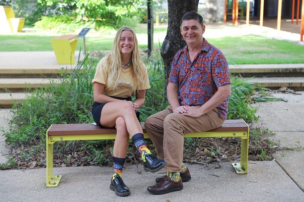 young woman and older man sitting on bench and wearing colourful socks