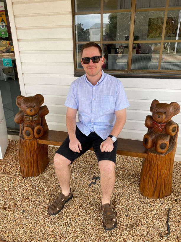 Man on bench with teddy bear carved legs