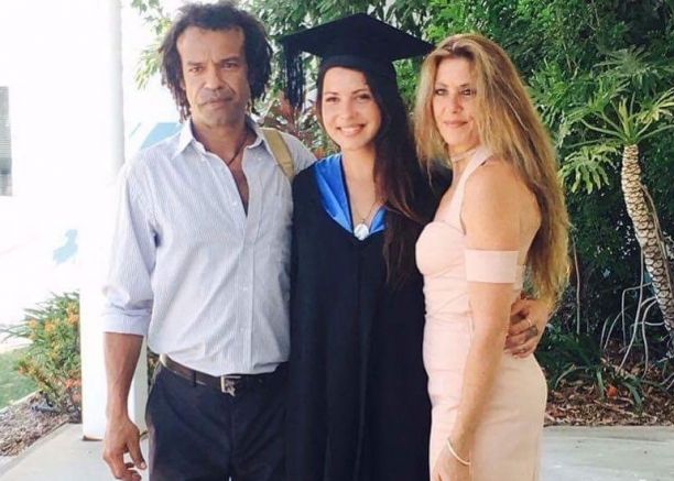 female uni graduate in cap and gown with parents