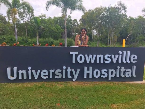 young woman leaning on Townsville University Hospital sign