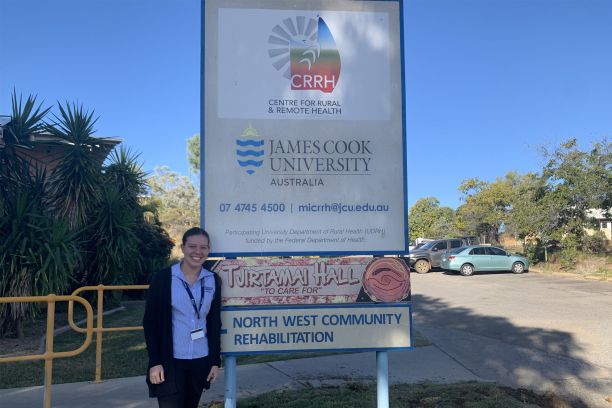 Jai-ann standing outside beside the sign for the Mount Isa Centre for Rural and Remote Health. 