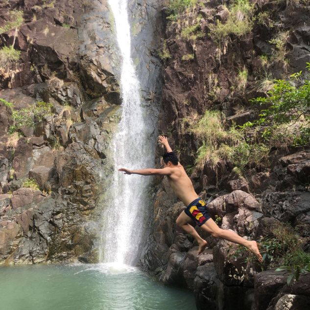 Man jumping in front of waterfall