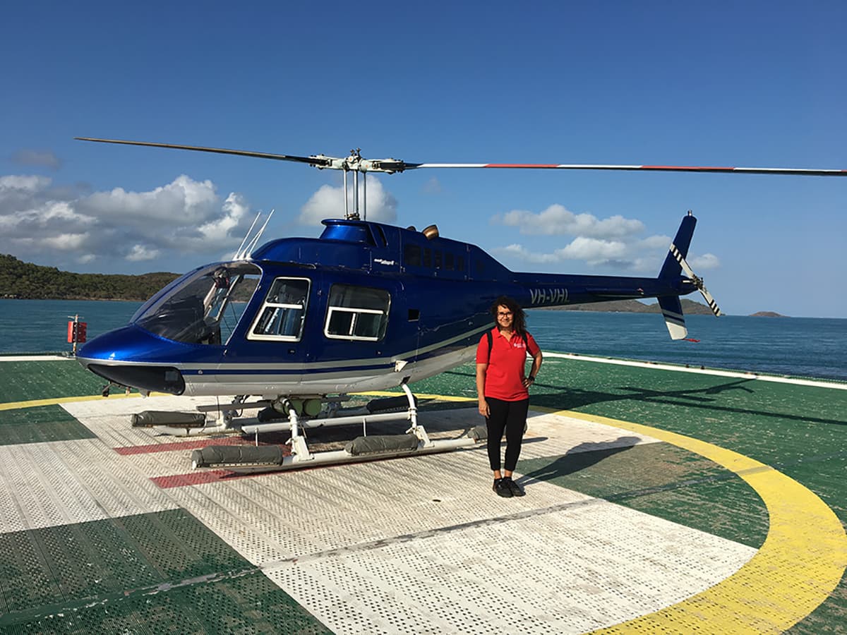 woman standing on helipad with helicopter in background