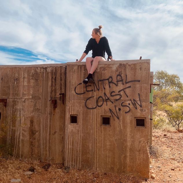 Young woman sitting on concrete block with grafffiti