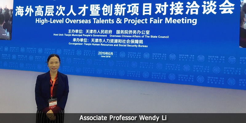 Wendy Li infront of confrence banner. 