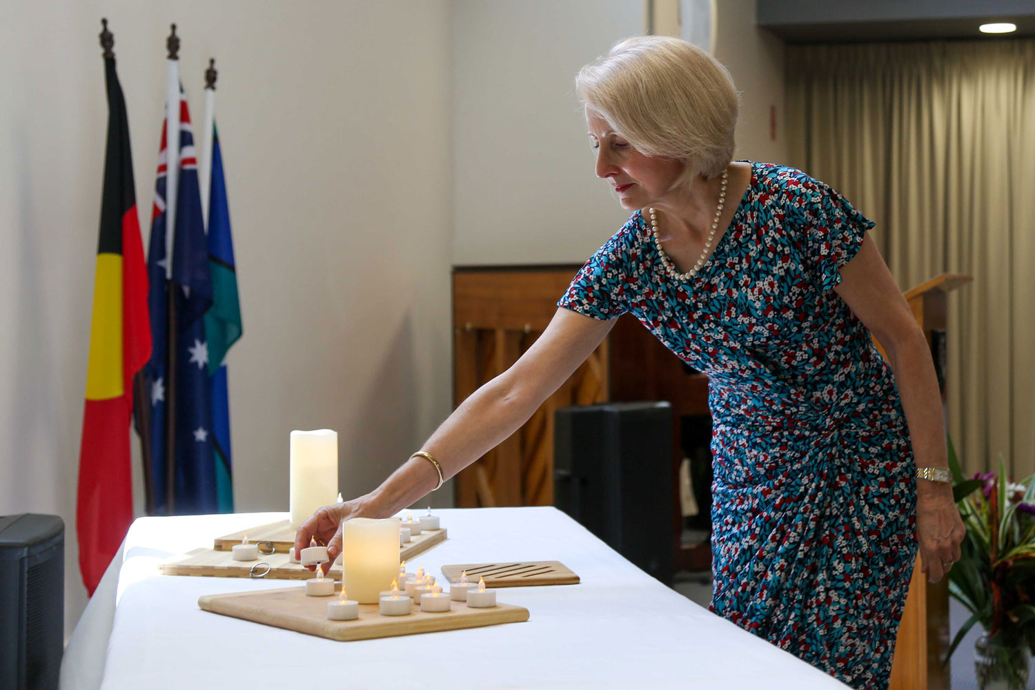 a woman reaches to place an electric candle on a table among others