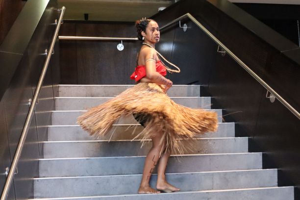 Simaema Wickham mid-spin, with her traditional grass skirt flaring around her. 