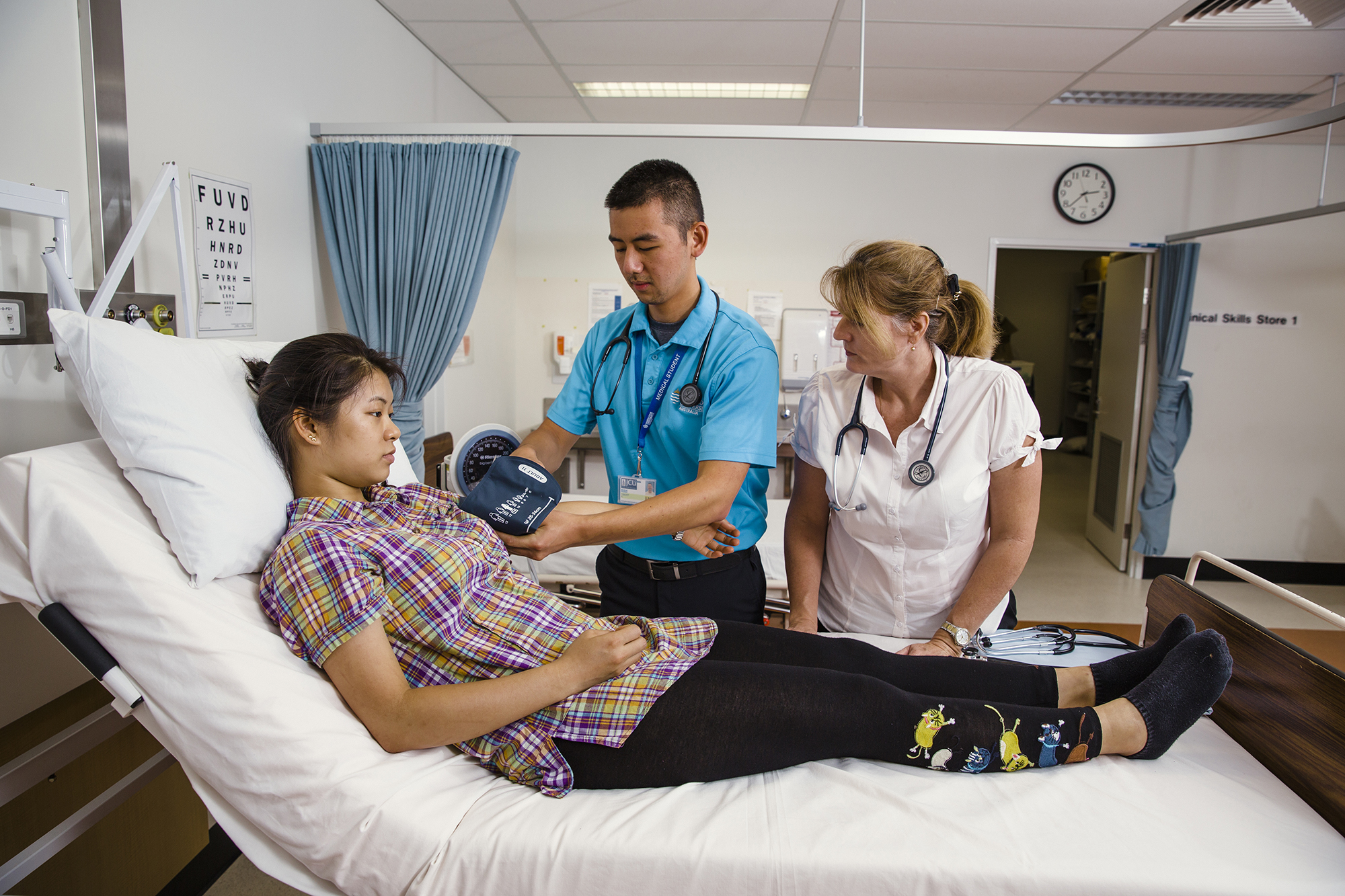 Teacher observing student examining patient