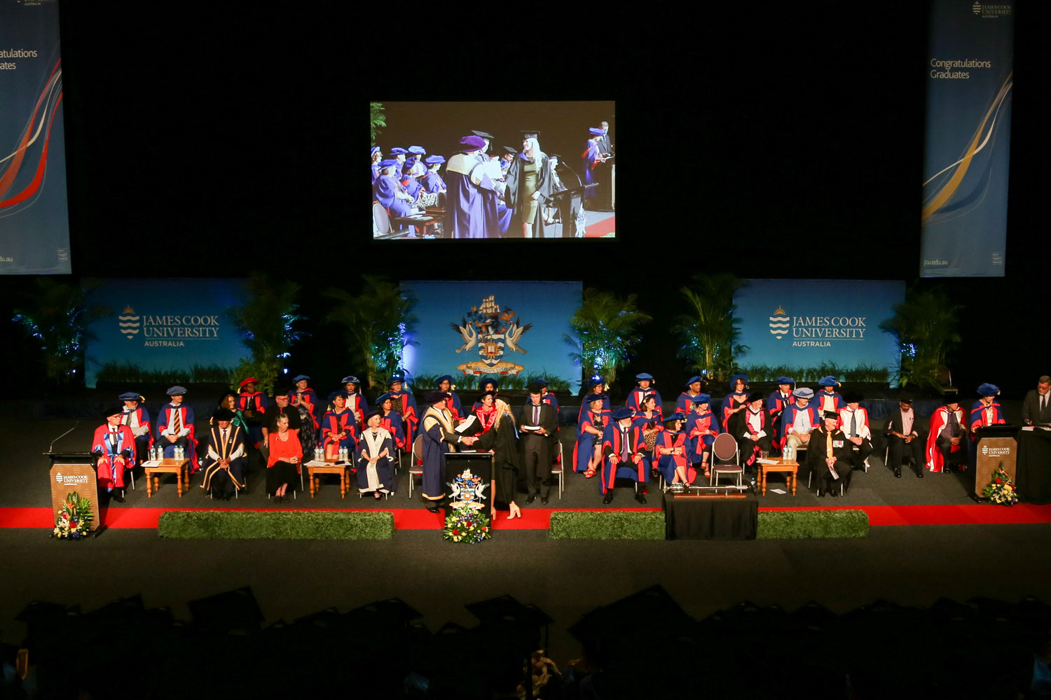 Long shot of the stage as a grad shakes hands with the chancellor