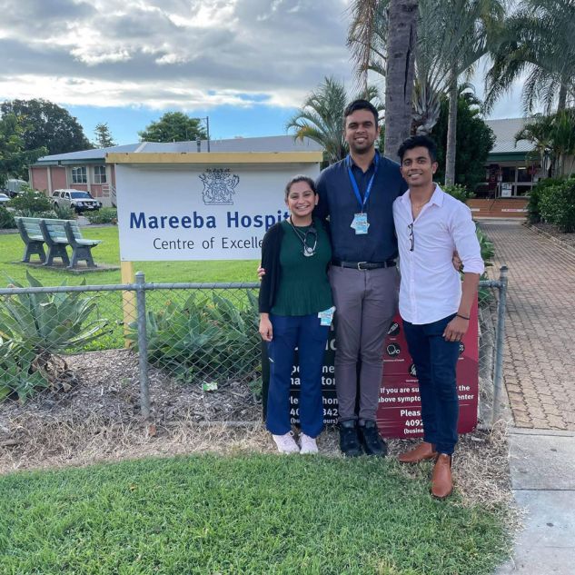 Three people outside Mareeba hospital sign