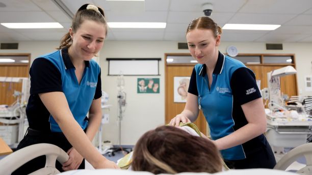 Two midwifery students encourage pregnant woman in hospital bed. 