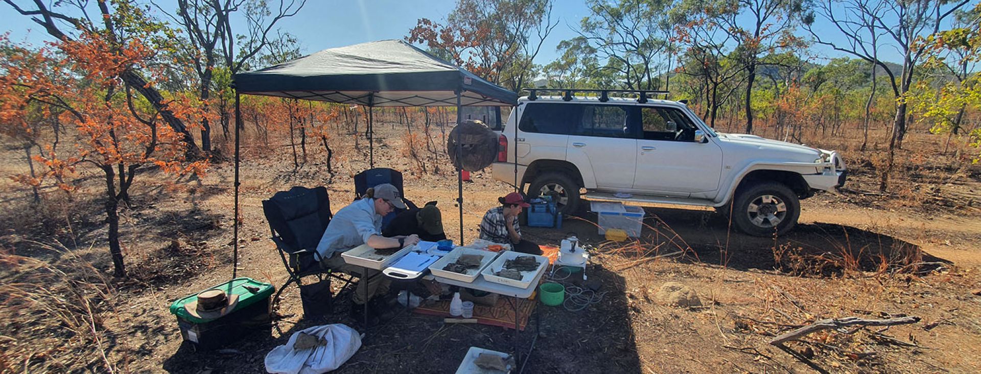 Two researchers working under shade in hot dry country. 