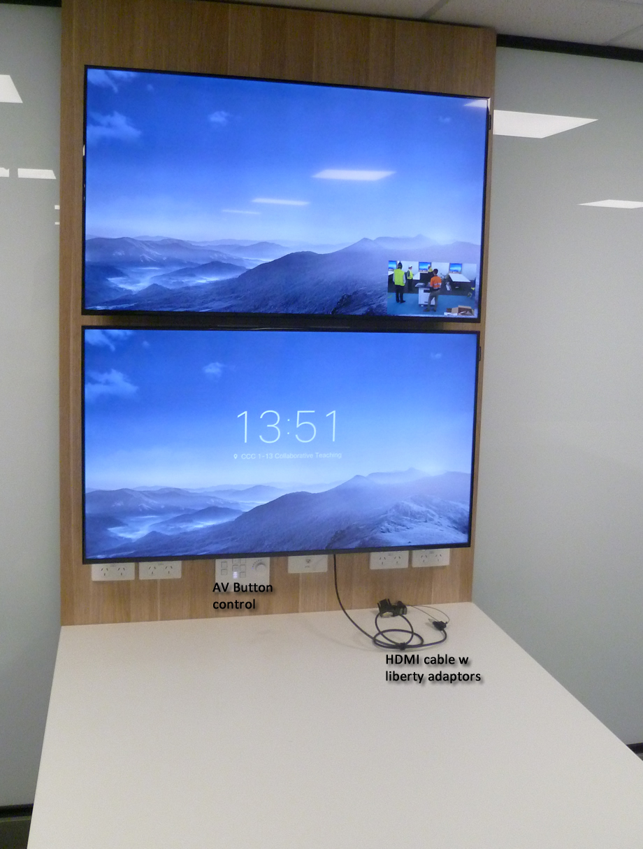 Two Monitors, mounted on a wall above eachother over a desk.