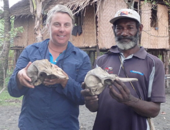 A JCU researcher with a local Papua New Guinean man. Both are holding animal skulls. 