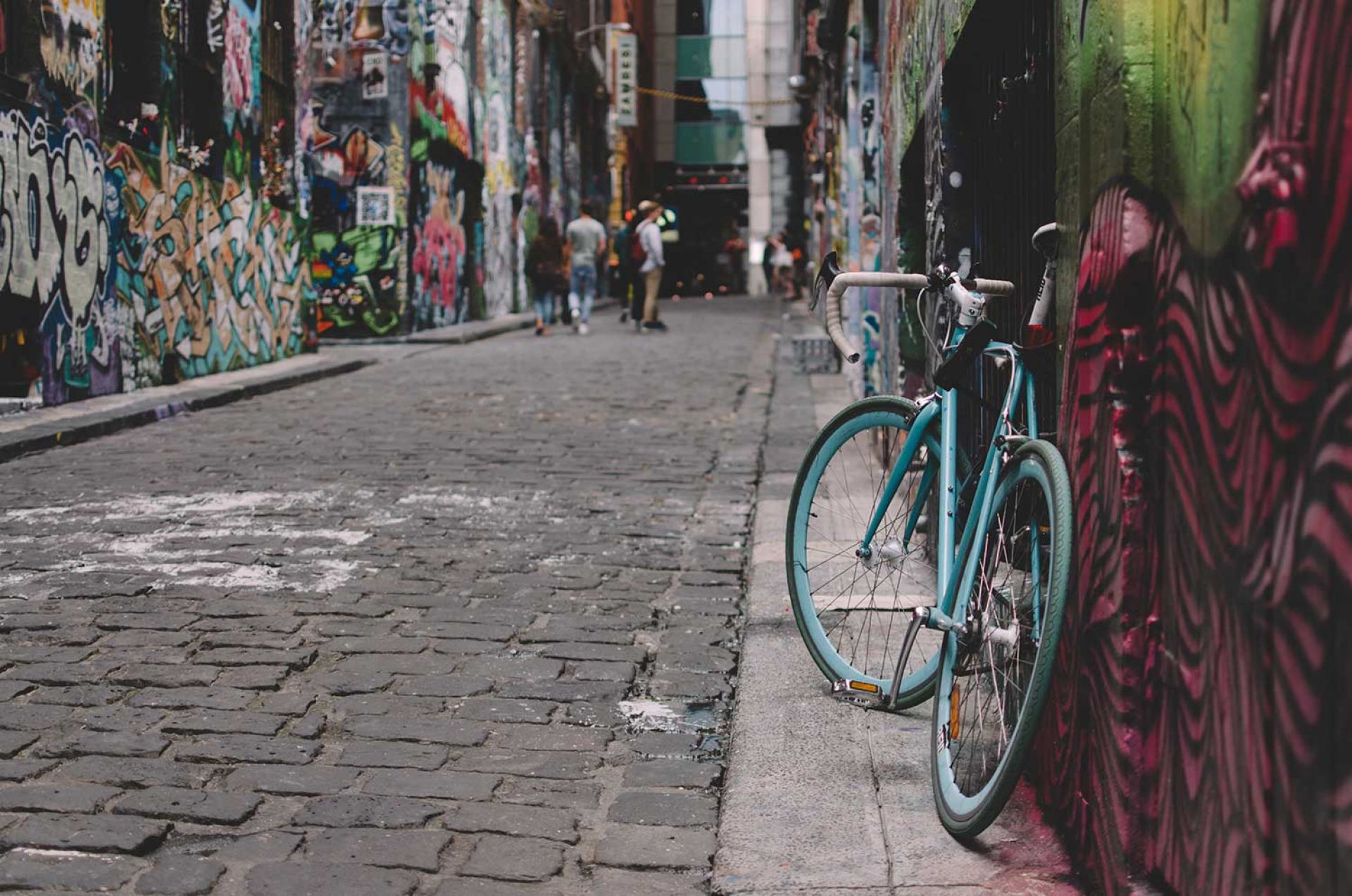 Green bicycle in the foreground of a photo of the graffiti art space, Hosier Lane