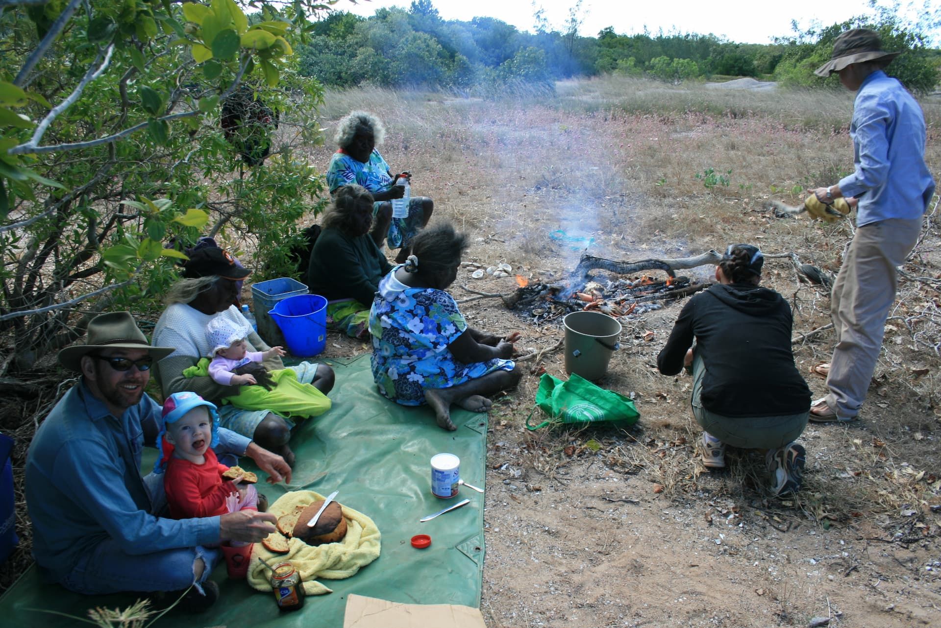 Elders sitting around a camp fire in the bush. 
