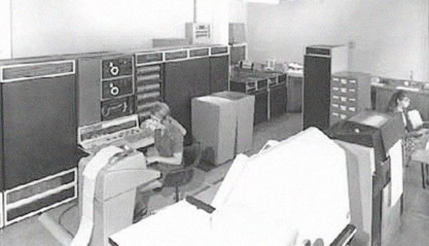 JCU computer lab in the 1970s with two people working in a room full of giant computers