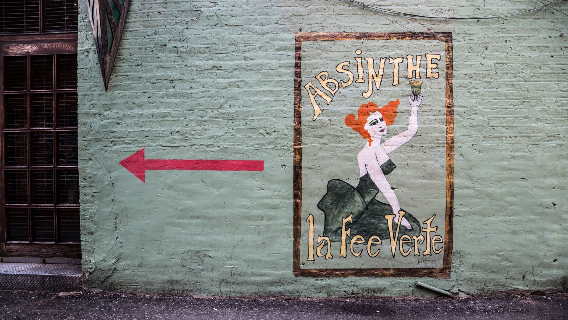 Absinthe mural on a grey wall, large red arrow pointing left