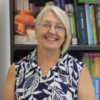 Michelle McElroy standing in front of bookshelf. 