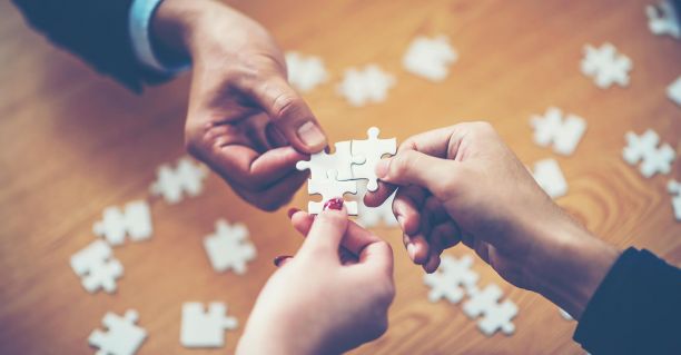 People putting together pieces of a jigsaw successfully. 